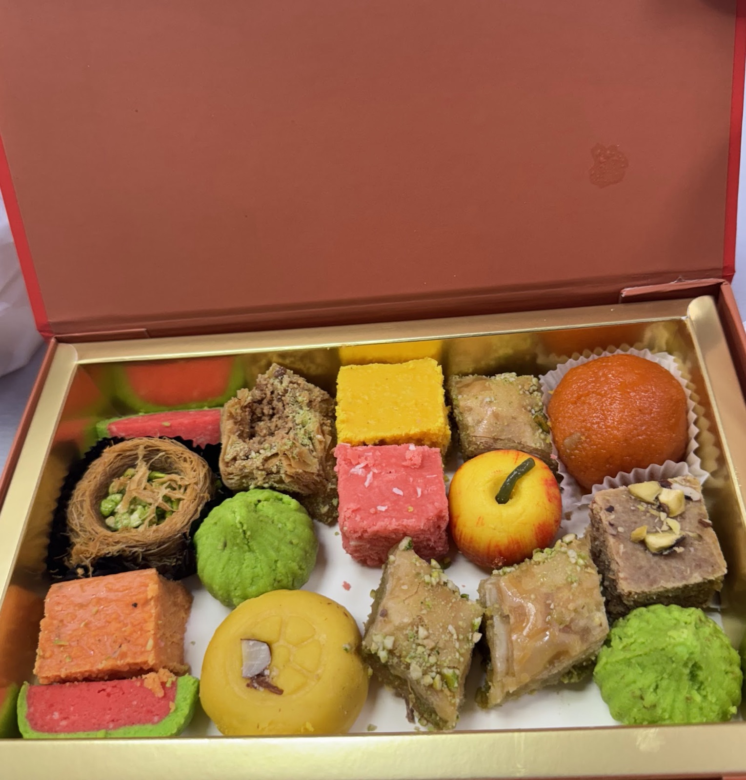 An open gift box of assorted Indian sweets from Jalaram Sweet Mart
